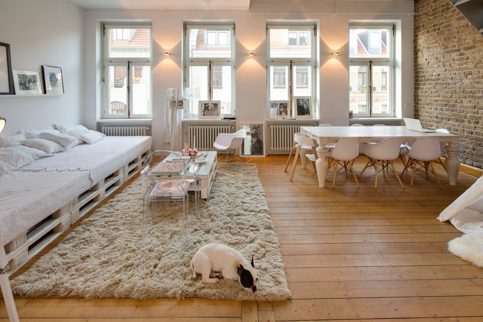 Example of a mid-sized urban open concept medium tone wood floor living room design in Cologne with white walls and no fireplace