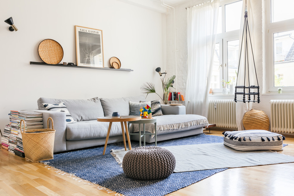 Diseño de sala de estar abierta actual de tamaño medio sin chimenea y televisor con paredes blancas, suelo de madera en tonos medios y suelo beige