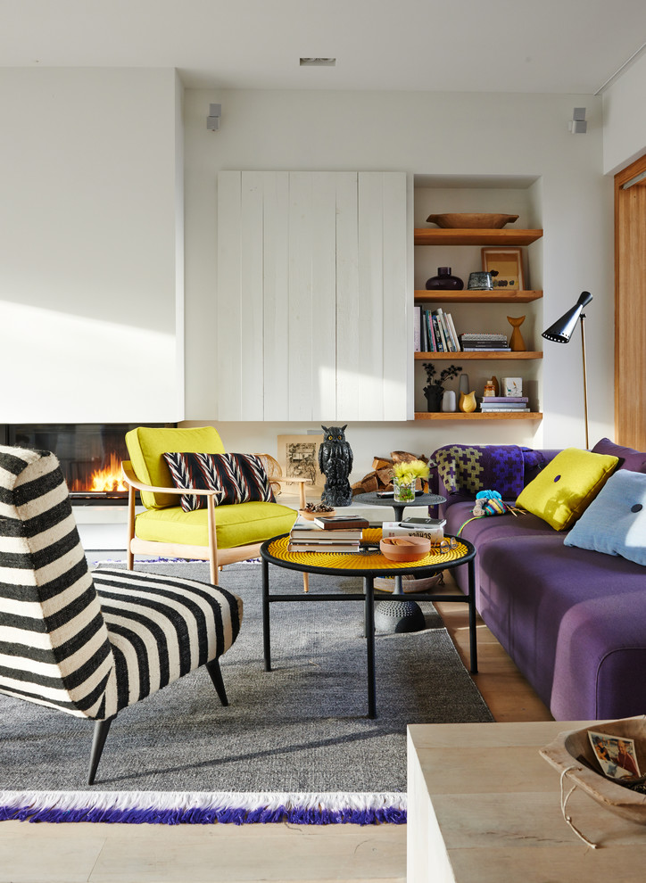 Example of a mid-sized danish enclosed medium tone wood floor family room design in Hamburg with a ribbon fireplace and white walls