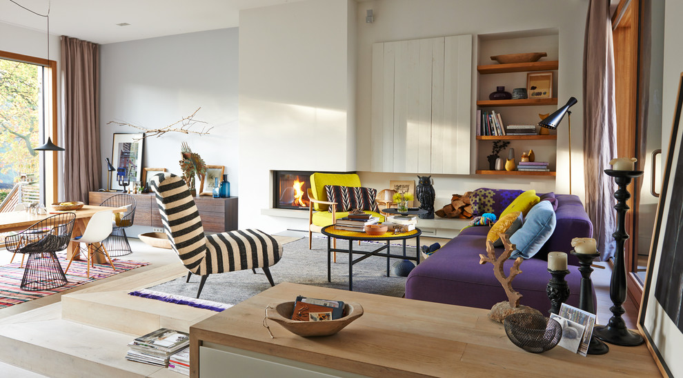 Стильный дизайн: открытая гостиная комната в скандинавском стиле с разноцветными стенами, светлым паркетным полом, двусторонним камином и фасадом камина из штукатурки без телевизора - последний тренд