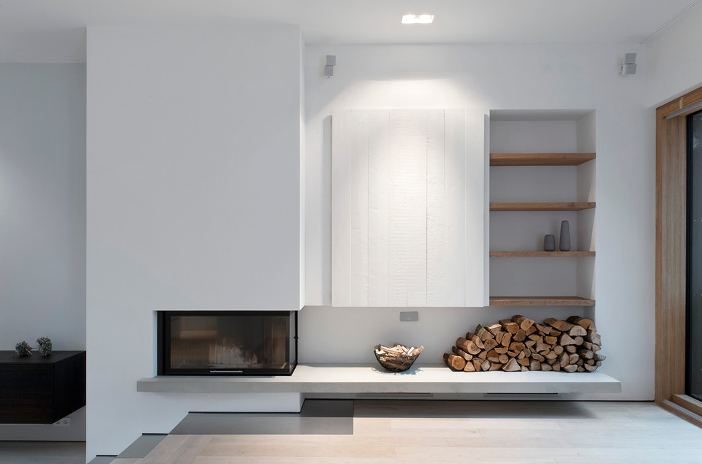 Imagen de sala de estar abierta escandinava con chimenea de esquina, paredes blancas, suelo de madera clara y marco de chimenea de yeso
