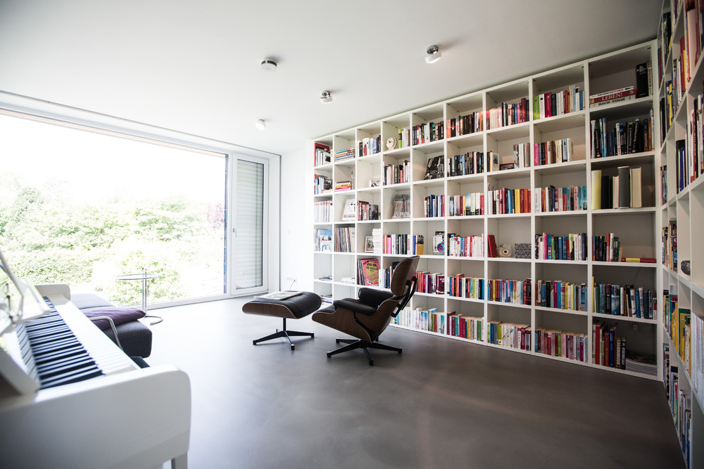 Idee per un soggiorno design con libreria, pareti bianche e pavimento in cemento
