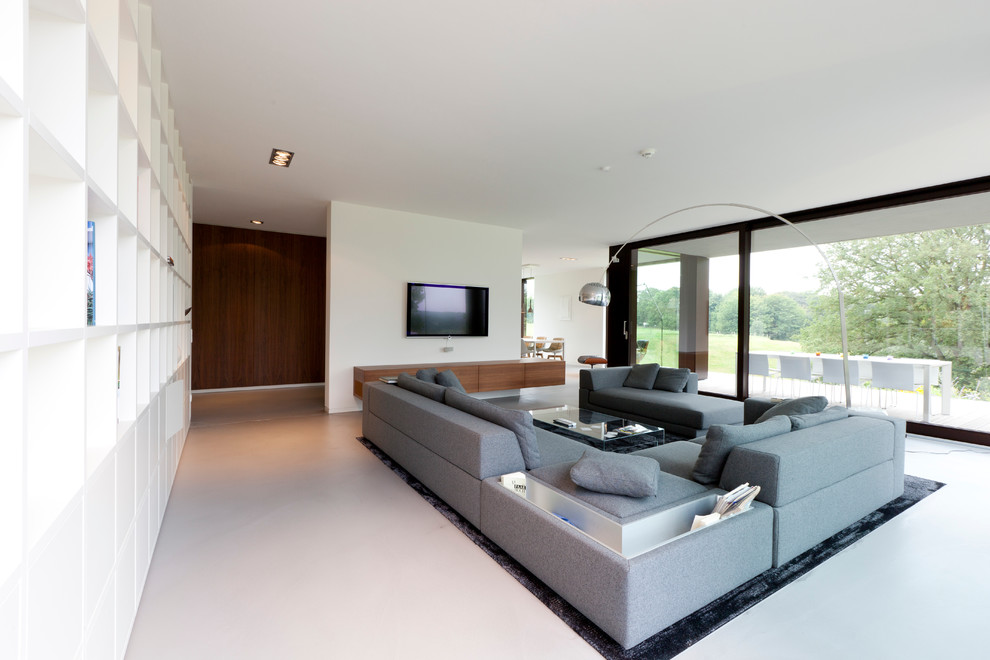 Offenes Modernes Wohnzimmer mit weißer Wandfarbe, Betonboden und TV-Wand in Düsseldorf