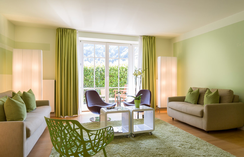 Imagen de salón para visitas cerrado contemporáneo grande sin chimenea y televisor con paredes verdes y suelo de madera en tonos medios