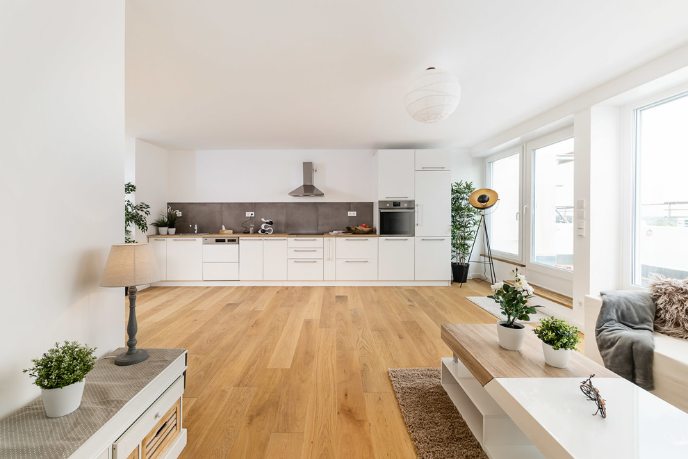 Geräumiges, Fernseherloses Skandinavisches Wohnzimmer ohne Kamin, im Loft-Stil mit weißer Wandfarbe, braunem Holzboden und braunem Boden in München