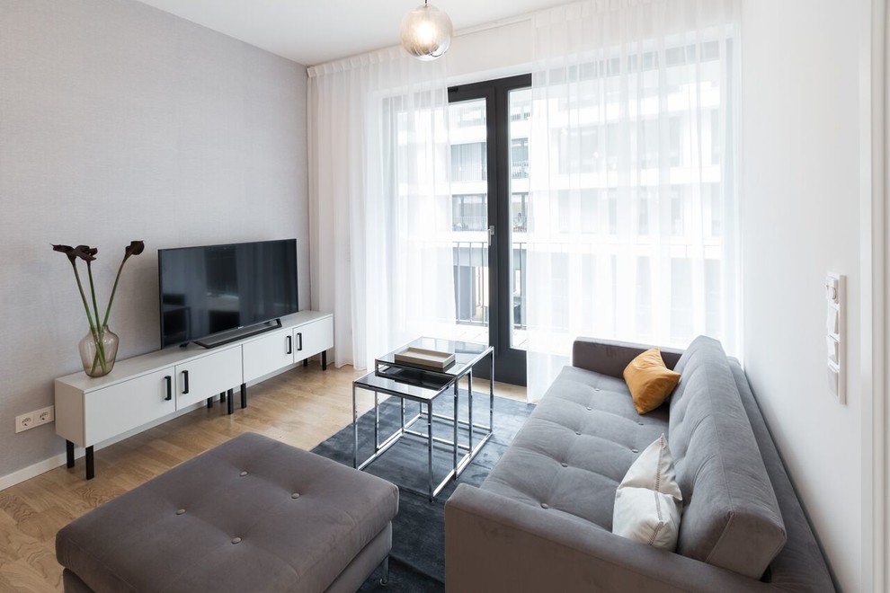 Idee per un piccolo soggiorno minimal chiuso con pareti grigie, parquet chiaro, TV autoportante e pavimento marrone