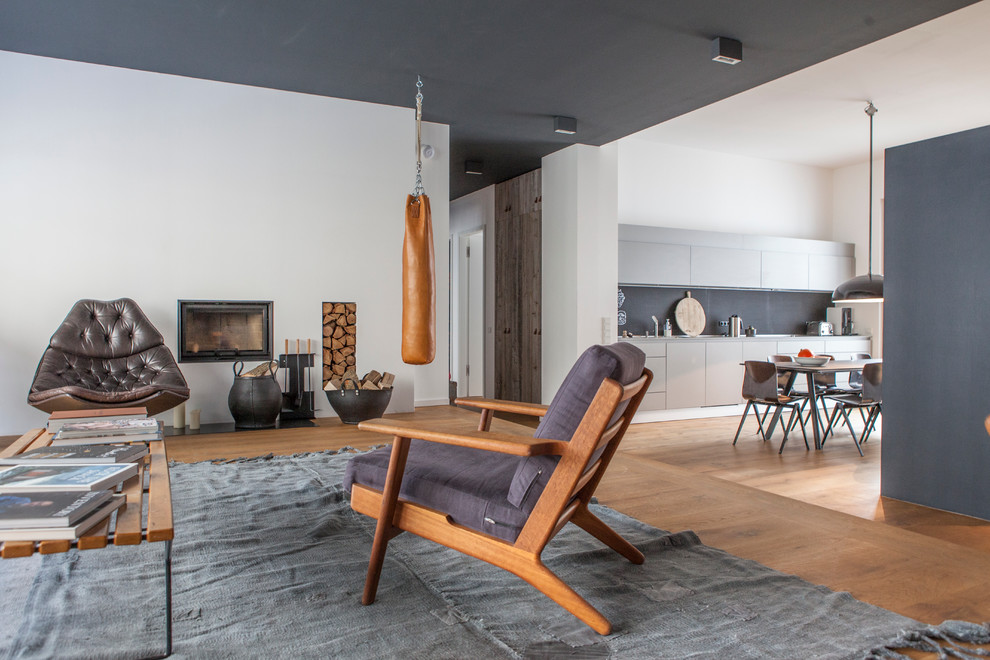 Foto de salón abierto nórdico de tamaño medio con paredes blancas, suelo de madera en tonos medios, todas las chimeneas y marco de chimenea de yeso