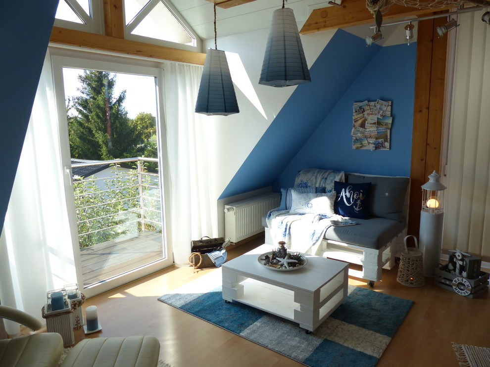 Modelo de sala de estar con biblioteca abierta marinera de tamaño medio sin chimenea y televisor con paredes azules y suelo de madera clara