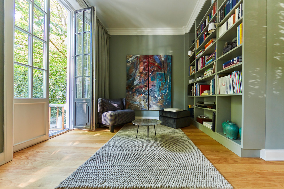 Пример оригинального дизайна: изолированная гостиная комната среднего размера в современном стиле с с книжными шкафами и полками, зелеными стенами, светлым паркетным полом, коричневым полом и ковром на полу без камина, телевизора
