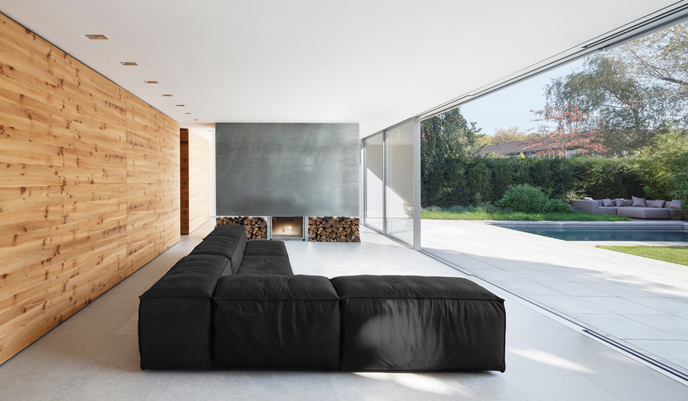 Esempio di un soggiorno minimalista di medie dimensioni e aperto con camino classico, cornice del camino in cemento, pareti grigie e nessuna TV