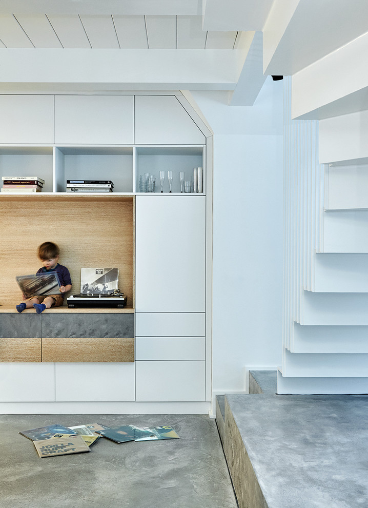 Immagine di un soggiorno design aperto con pavimento in cemento e pareti bianche