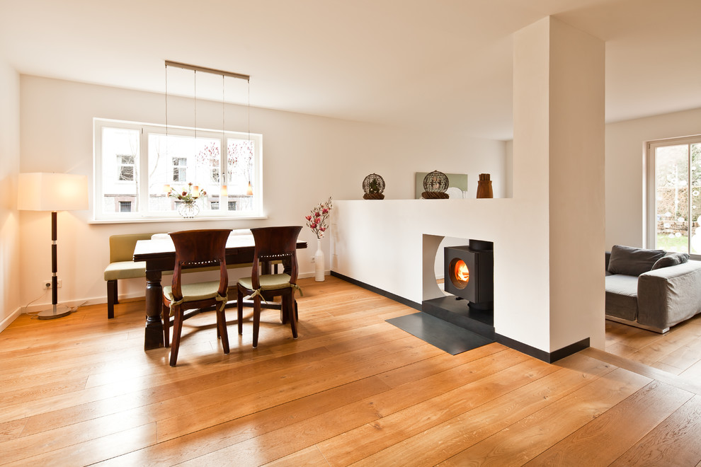 Abgetrenntes Modernes Wohnzimmer mit weißer Wandfarbe, hellem Holzboden, Hängekamin, verputzter Kaminumrandung und beigem Boden in Sonstige