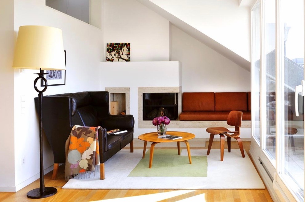 Immagine di un grande soggiorno minimalista stile loft con pareti bianche, camino ad angolo, cornice del camino in intonaco, pavimento in legno massello medio e pavimento marrone