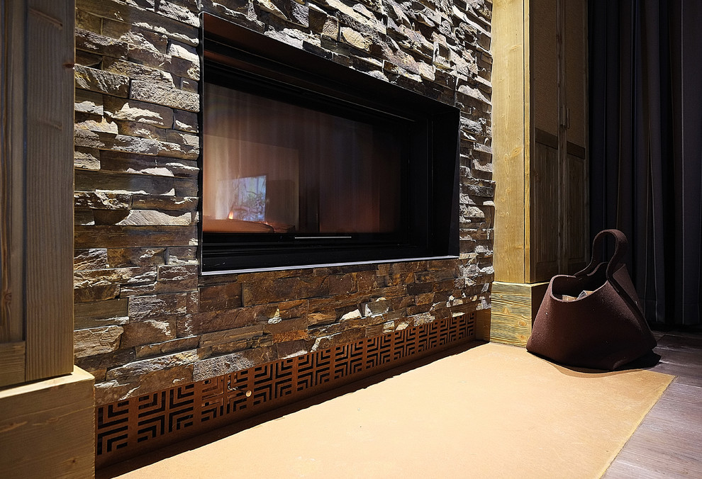 Foto de salón para visitas cerrado rústico grande con suelo de madera oscura, chimenea de doble cara, marco de chimenea de piedra y suelo marrón