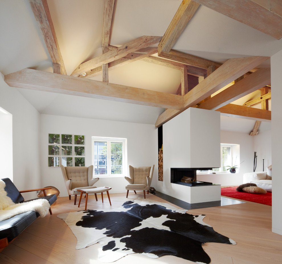 This is an example of an expansive contemporary open plan living room in Frankfurt with white walls, light hardwood flooring, a two-sided fireplace and a plastered fireplace surround.