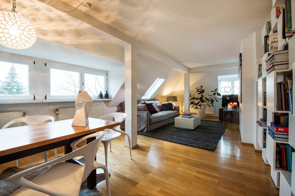 Modelo de sala de estar abierta contemporánea de tamaño medio con paredes blancas, suelo de madera en tonos medios y suelo marrón