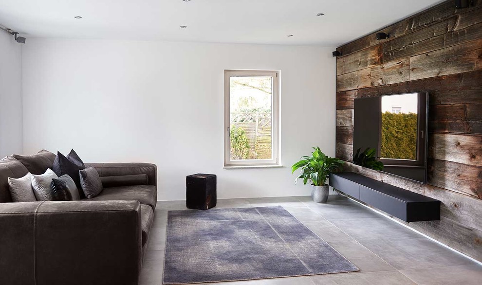 Foto di un soggiorno design di medie dimensioni con pareti bianche, pavimento in cemento, TV a parete e pavimento grigio