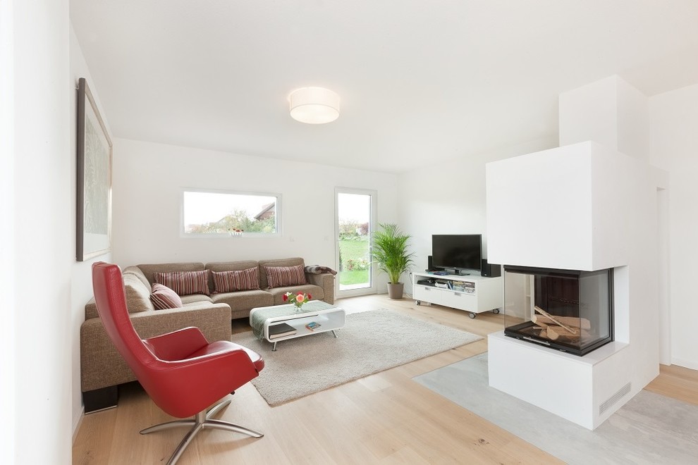 Großes, Offenes Modernes Wohnzimmer mit weißer Wandfarbe, hellem Holzboden, Kaminofen, verputzter Kaminumrandung, freistehendem TV und braunem Boden in Stuttgart