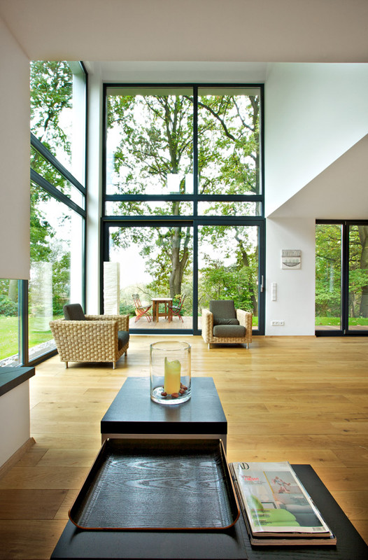 Großes, Offenes Modernes Wohnzimmer mit weißer Wandfarbe, hellem Holzboden, Eckkamin und verputzter Kaminumrandung in Hannover