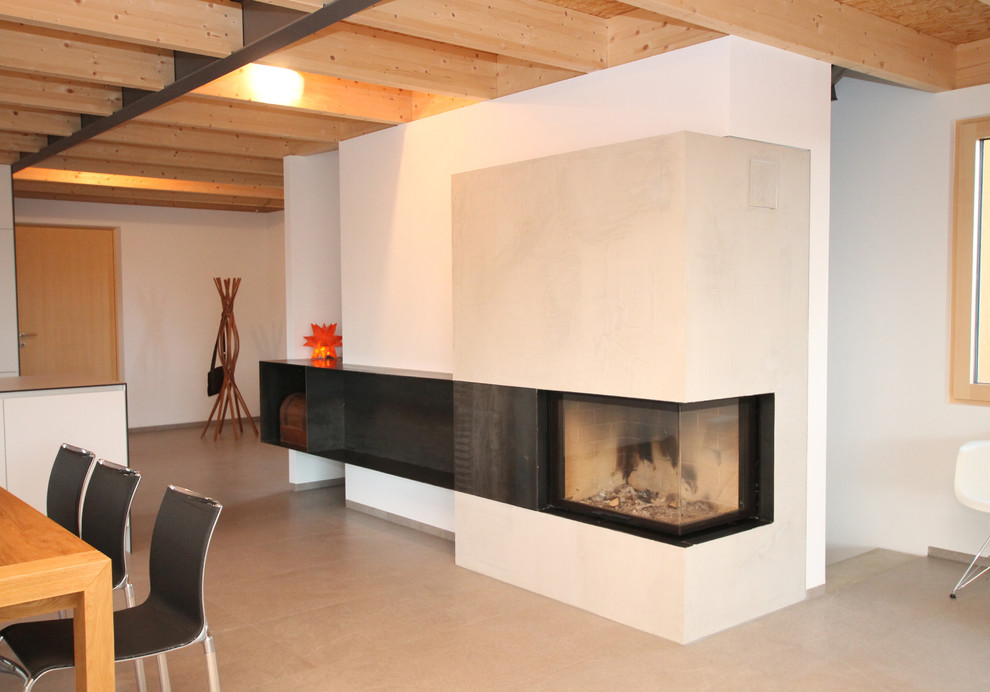 Cette photo montre un salon tendance ouvert avec un mur blanc et un manteau de cheminée en béton.