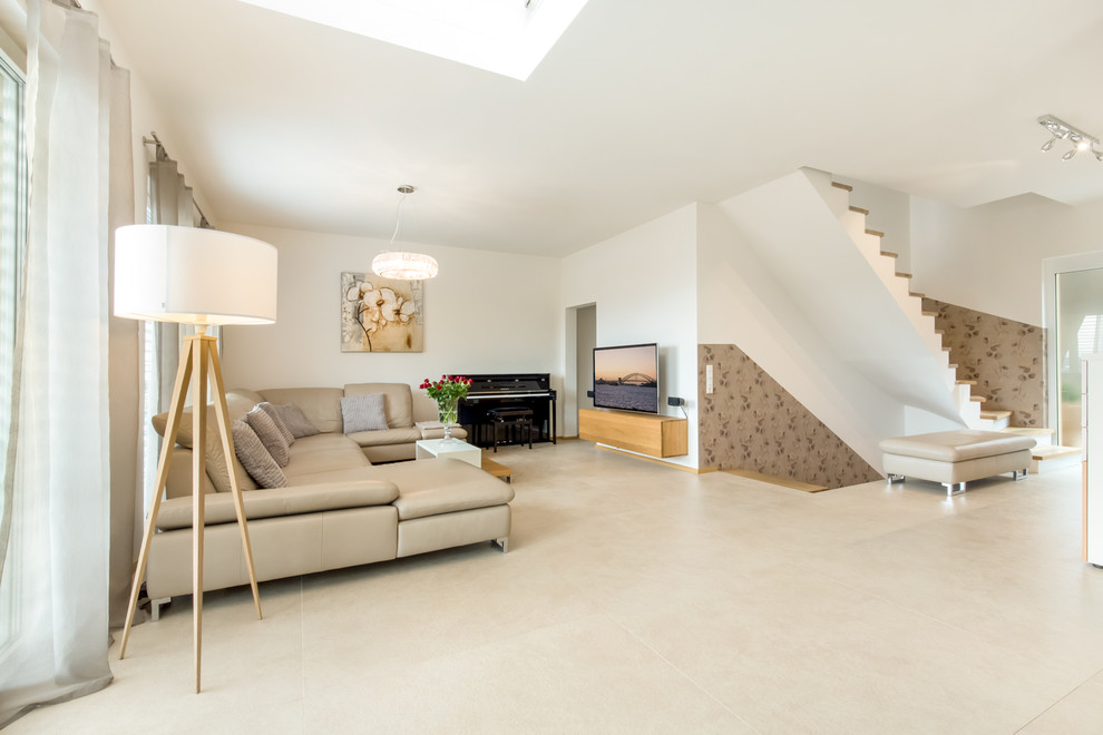 Immagine di un soggiorno minimal di medie dimensioni e aperto con pavimento in pietra calcarea, TV a parete e pareti bianche