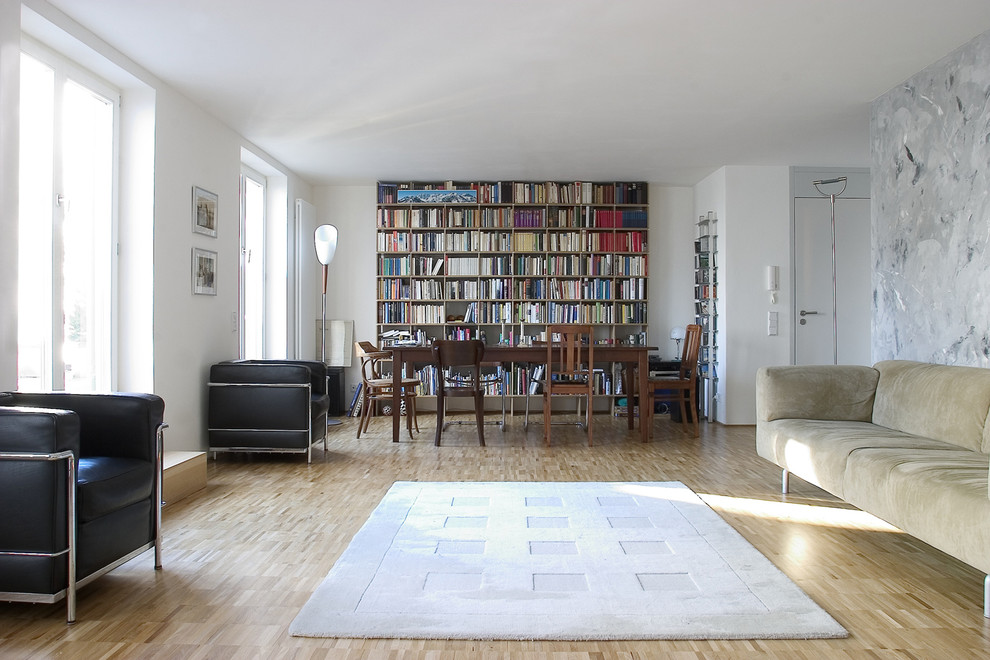 Foto på ett stort funkis allrum med öppen planlösning, med ett bibliotek, vita väggar och ljust trägolv