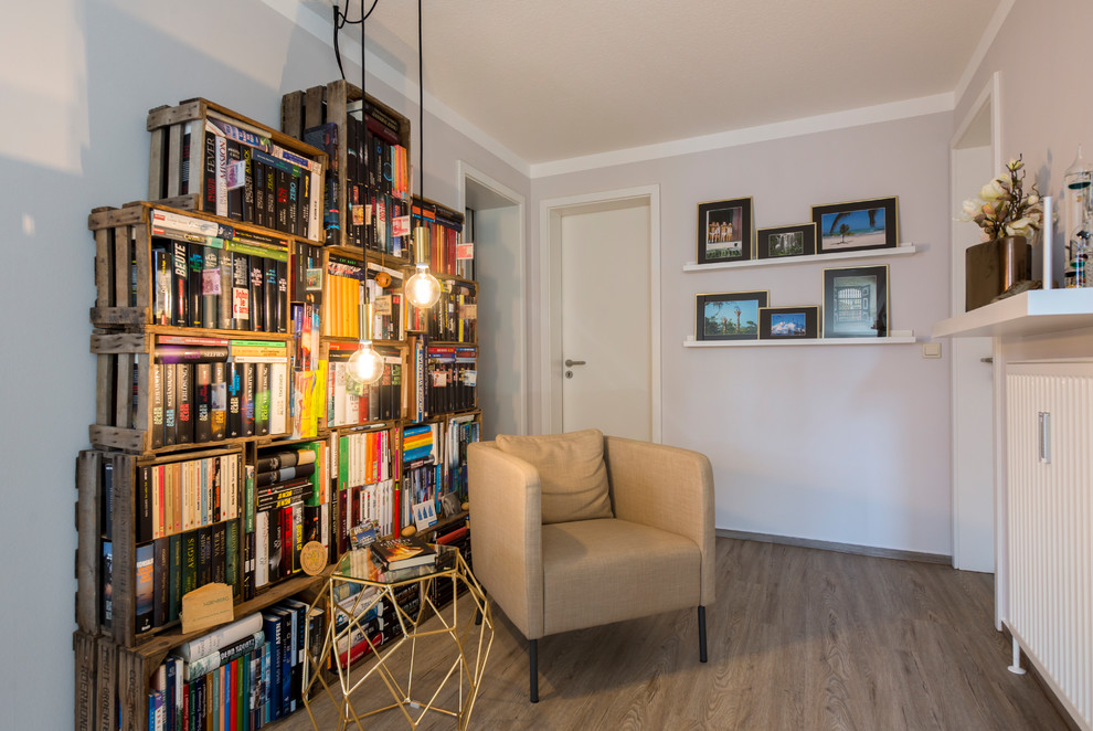 Ispirazione per un piccolo soggiorno design con libreria, pareti grigie, nessun camino, nessuna TV e pavimento in legno massello medio