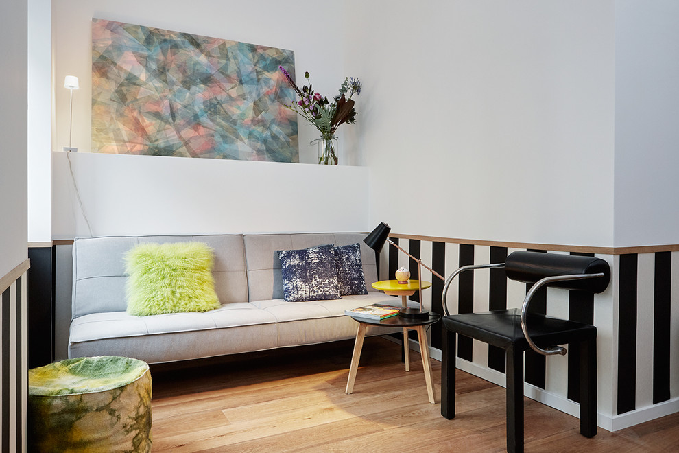 Kleines, Offenes, Fernseherloses Modernes Wohnzimmer ohne Kamin mit hellem Holzboden, weißer Wandfarbe und braunem Boden in Düsseldorf