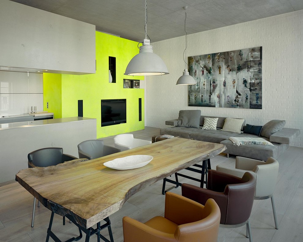Bild på ett mycket stort funkis vardagsrum, med gula väggar, en väggmonterad TV och ljust trägolv