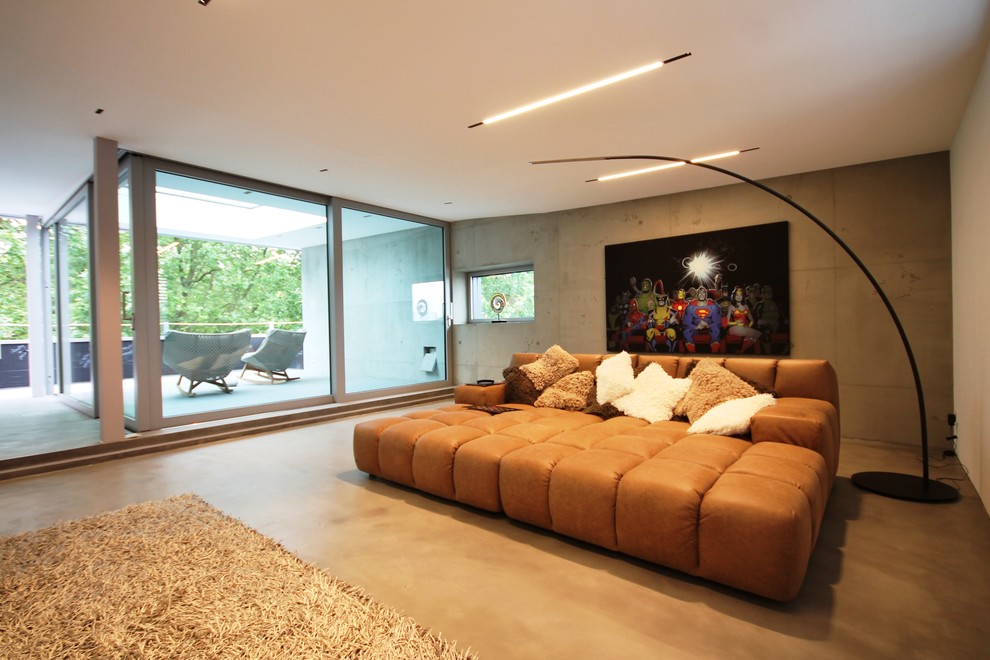Diseño de sala de estar abierta industrial extra grande con paredes grises y suelo de cemento