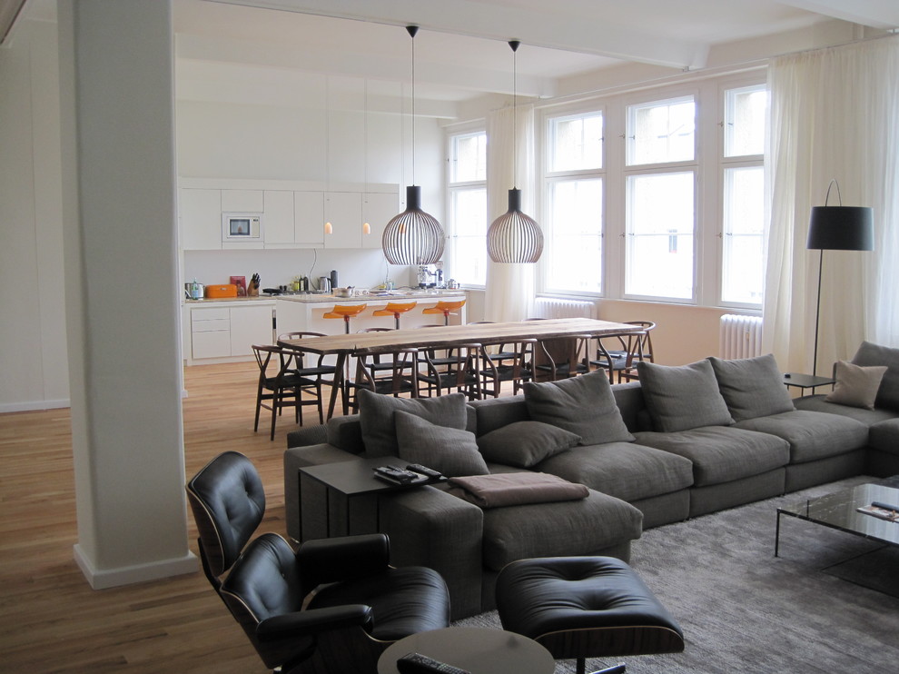 Modelo de sala de estar abierta actual de tamaño medio con paredes blancas y suelo de madera en tonos medios