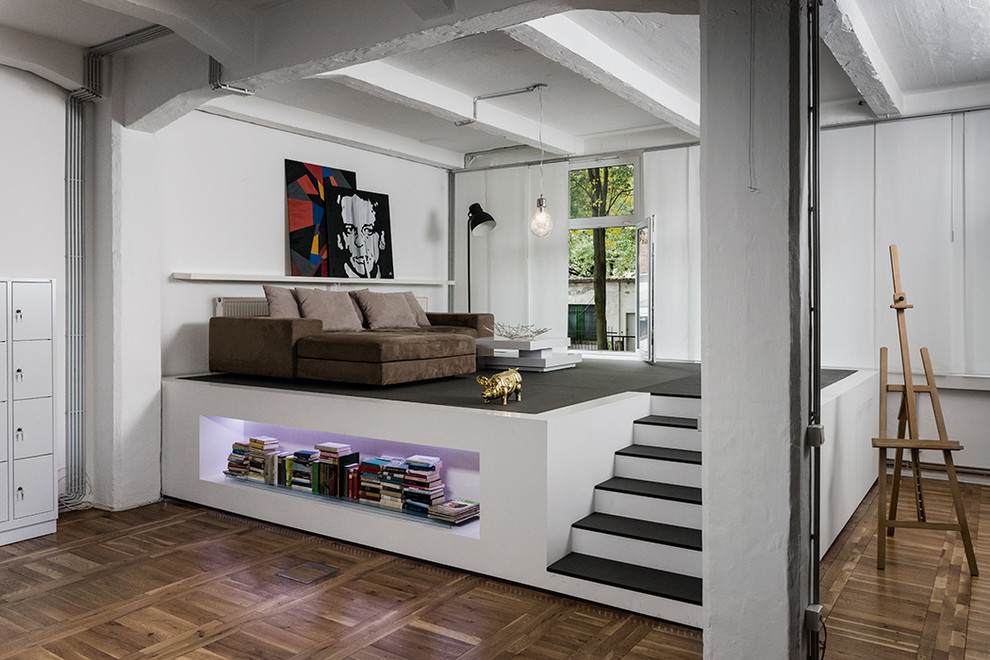 Kleines, Fernseherloses Industrial Wohnzimmer ohne Kamin, im Loft-Stil mit weißer Wandfarbe und braunem Holzboden in Sonstige