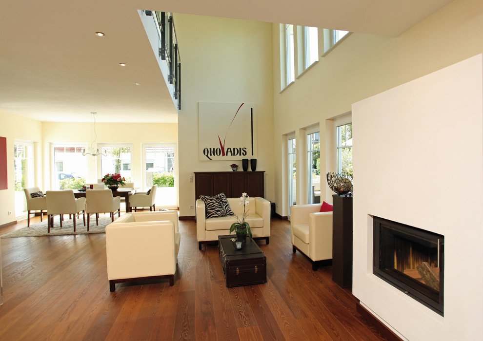 Cette photo montre un salon tendance ouvert avec un mur beige, un sol en bois brun, un poêle à bois, un manteau de cheminée en plâtre et un sol marron.