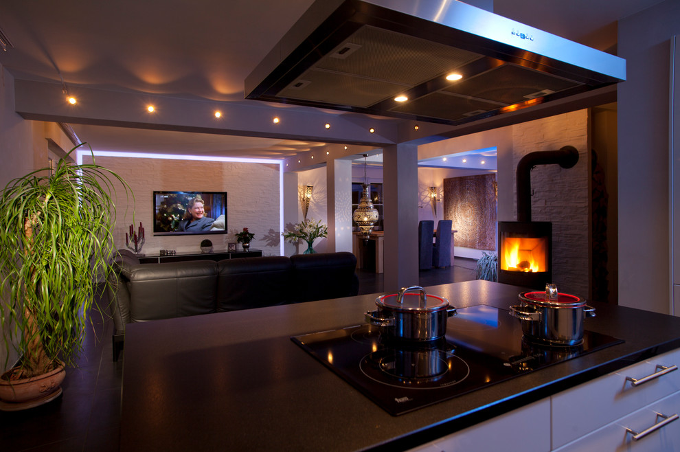 ケルンにある高級な広いインダストリアルスタイルのおしゃれなオープンリビング (白い壁、セラミックタイルの床、標準型暖炉、金属の暖炉まわり、壁掛け型テレビ、黒い床) の写真