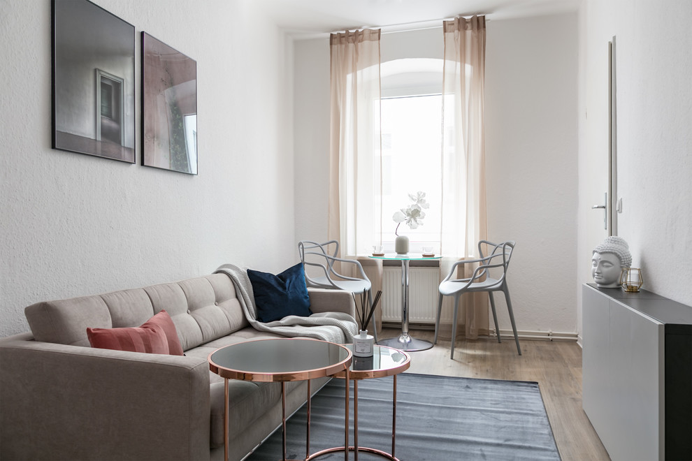 Diseño de sala de estar cerrada contemporánea pequeña sin chimenea y televisor con paredes blancas, suelo de madera en tonos medios y suelo marrón