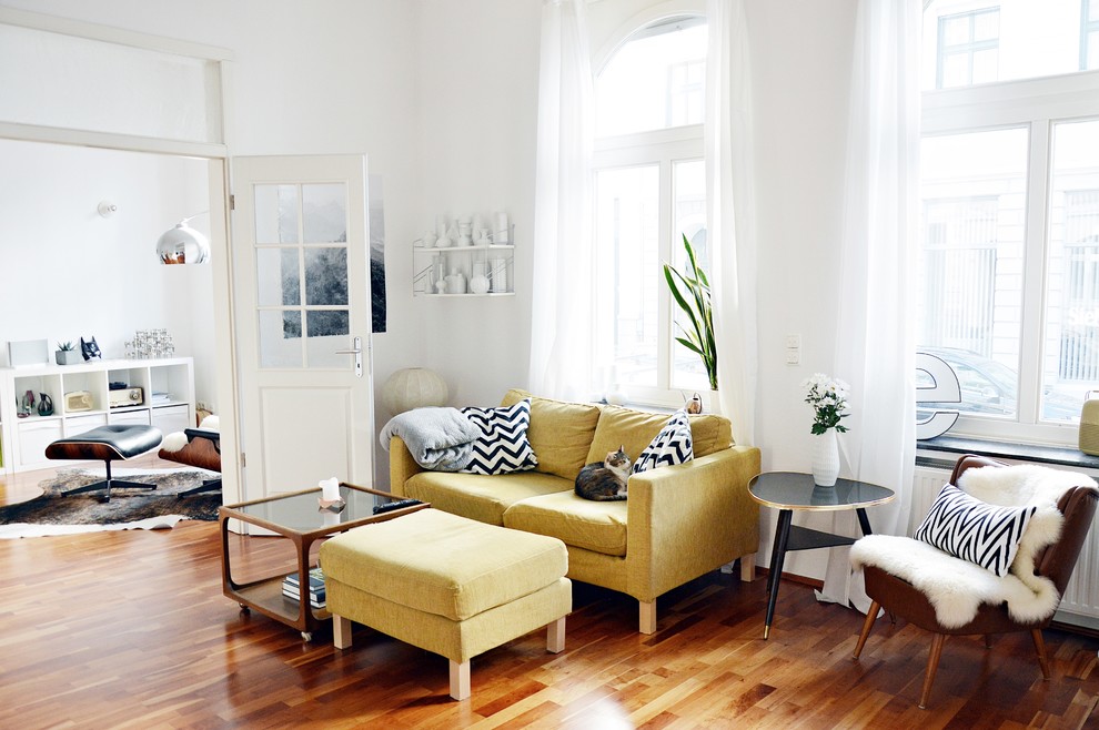 This is an example of a medium sized scandinavian enclosed living room in Dusseldorf with white walls, medium hardwood flooring and no fireplace.