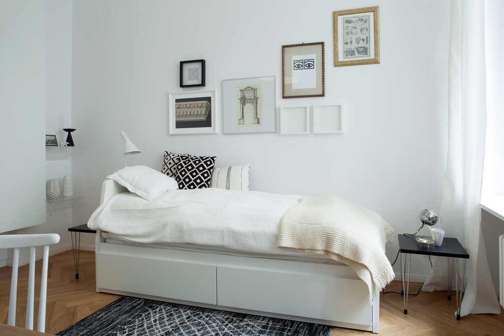 Imagen de dormitorio escandinavo pequeño sin chimenea con paredes blancas, suelo de madera en tonos medios y suelo marrón
