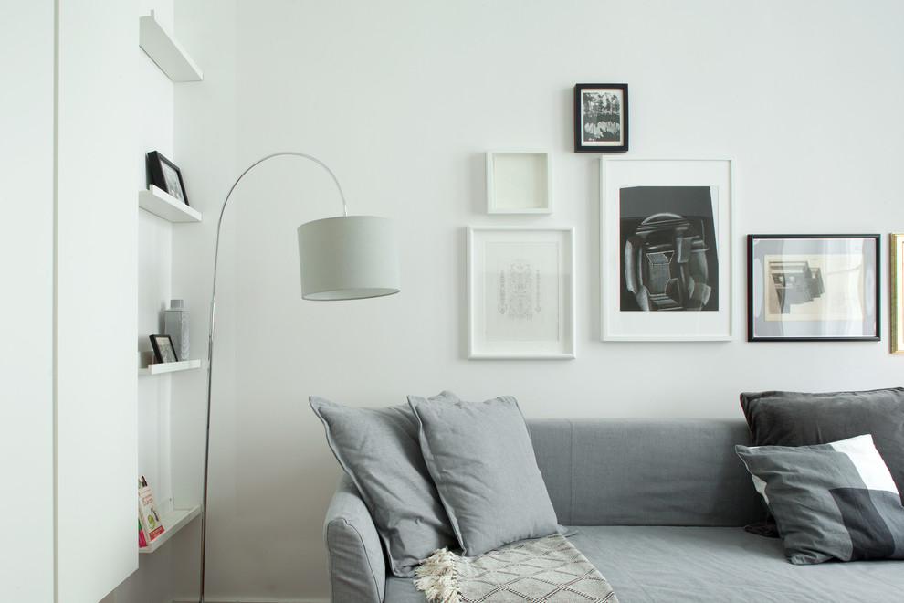 На фото: маленькая двухуровневая гостиная комната в скандинавском стиле с белыми стенами, полом из ламината и коричневым полом без камина, телевизора для на участке и в саду с