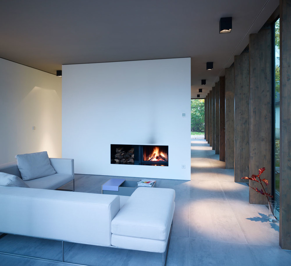 Idee per un soggiorno minimalista aperto e di medie dimensioni con pareti bianche, pavimento in cemento, camino classico e cornice del camino in intonaco