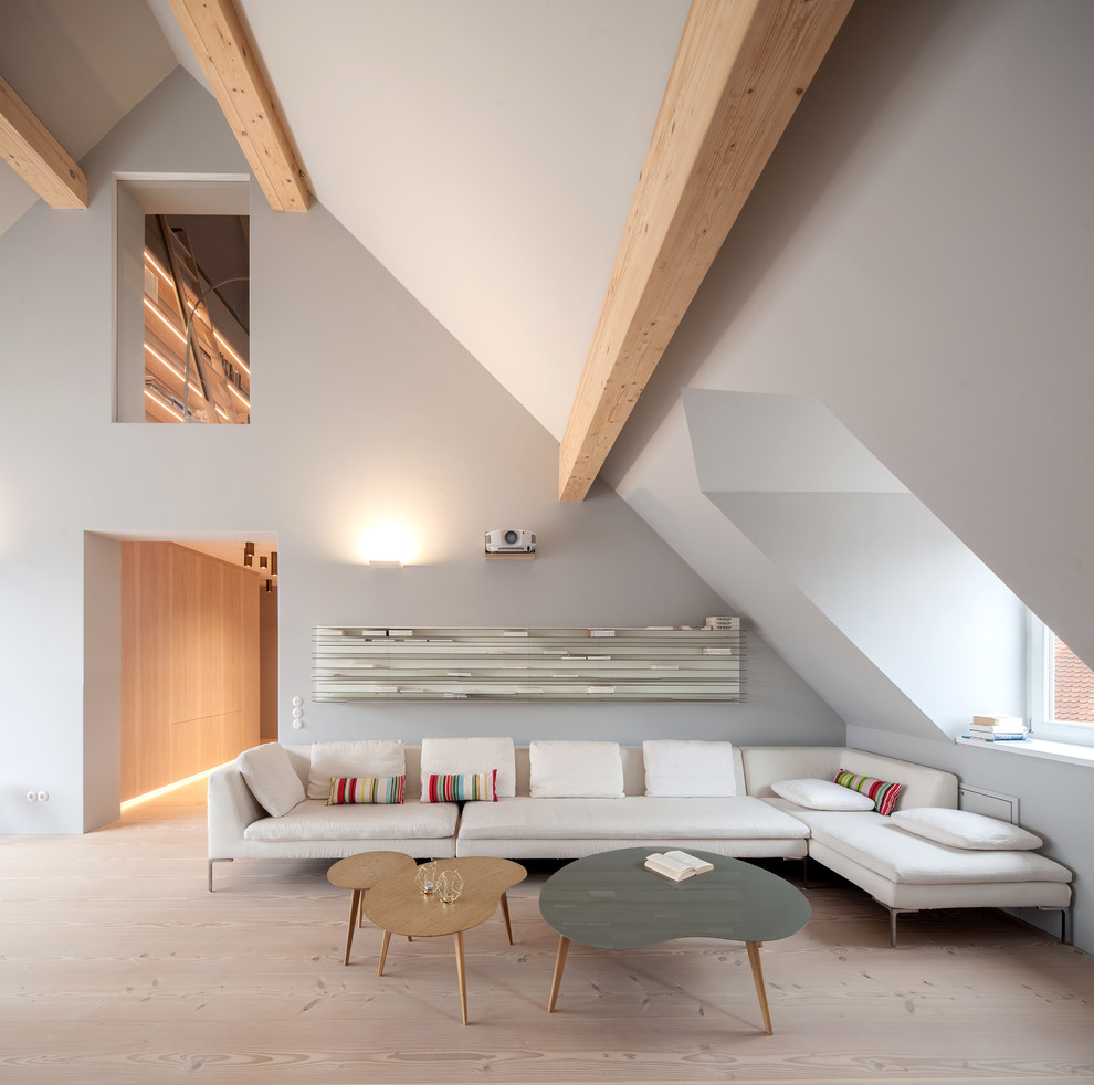 Foto de sala de estar abierta actual de tamaño medio con suelo de madera clara y paredes grises