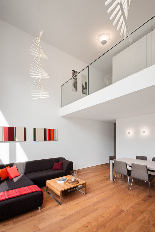 Diseño de salón abierto actual de tamaño medio sin chimenea con paredes blancas y suelo de madera en tonos medios