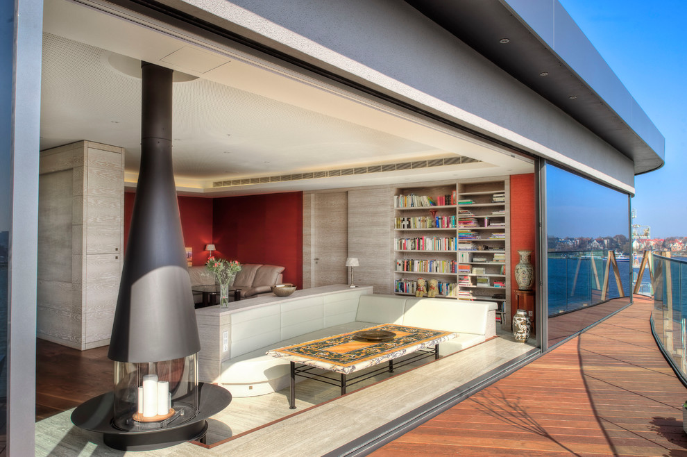 Foto di un grande soggiorno minimal aperto con libreria, pareti rosse, camino sospeso e pavimento in legno massello medio