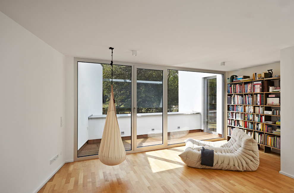 Immagine di un piccolo soggiorno contemporaneo chiuso con libreria, pareti bianche, parquet chiaro, nessuna TV e nessun camino