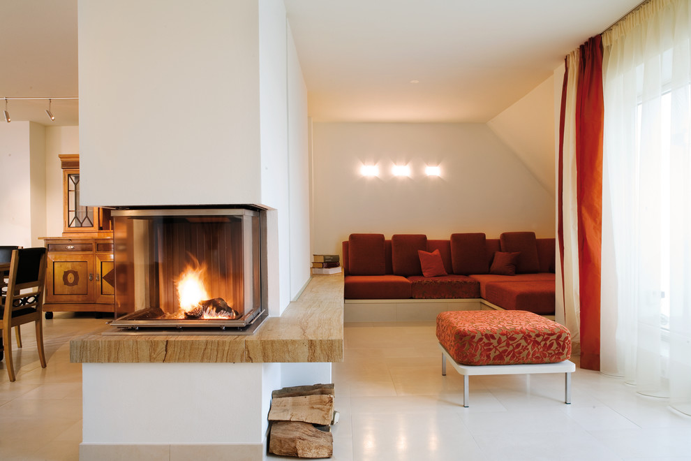 Imagen de sala de estar abierta contemporánea de tamaño medio con paredes beige, chimenea de doble cara y marco de chimenea de piedra