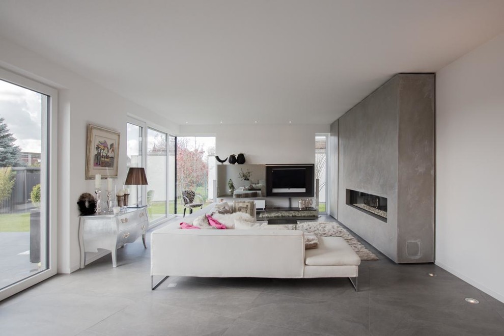 Mittelgroßes, Offenes Modernes Wohnzimmer mit weißer Wandfarbe, Betonboden, Gaskamin, TV-Wand und Kaminumrandung aus Beton in Berlin