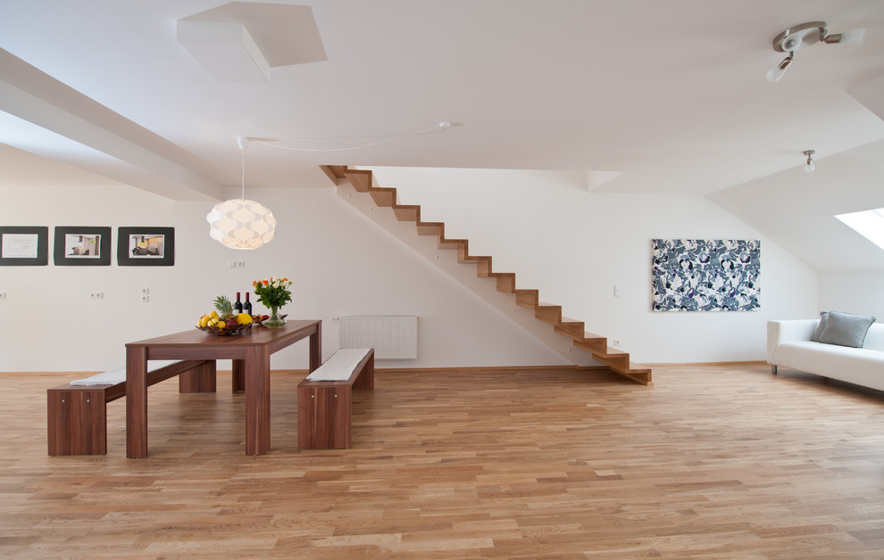 Modelo de sala de estar abierta actual de tamaño medio sin chimenea y televisor con paredes blancas y suelo de madera en tonos medios