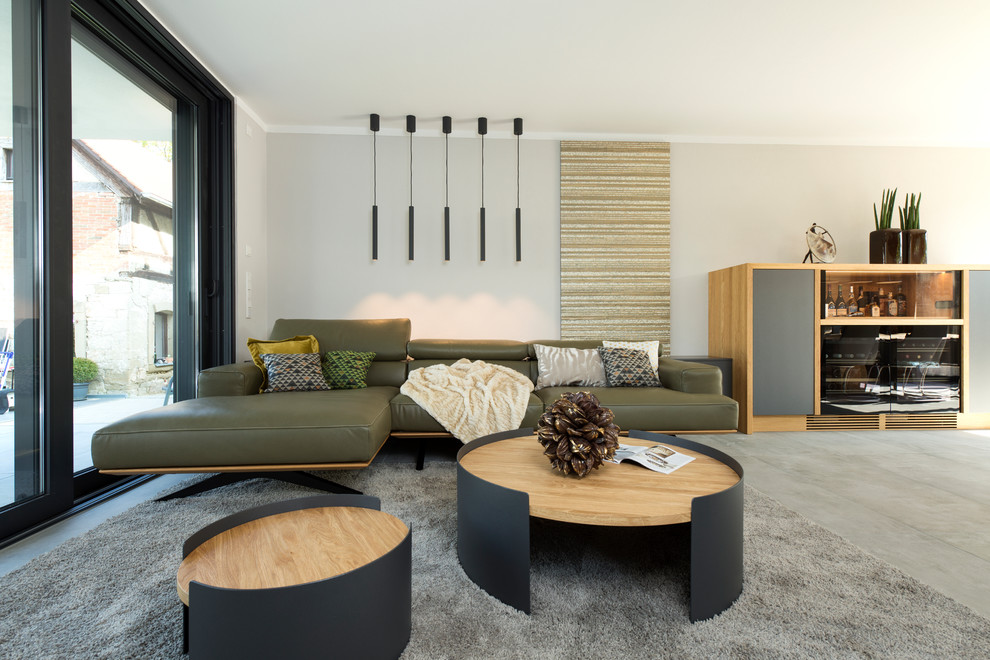 Mittelgroßes, Fernseherloses, Offenes Modernes Wohnzimmer ohne Kamin mit grauer Wandfarbe, Betonboden, grauem Boden und Hausbar in Nürnberg