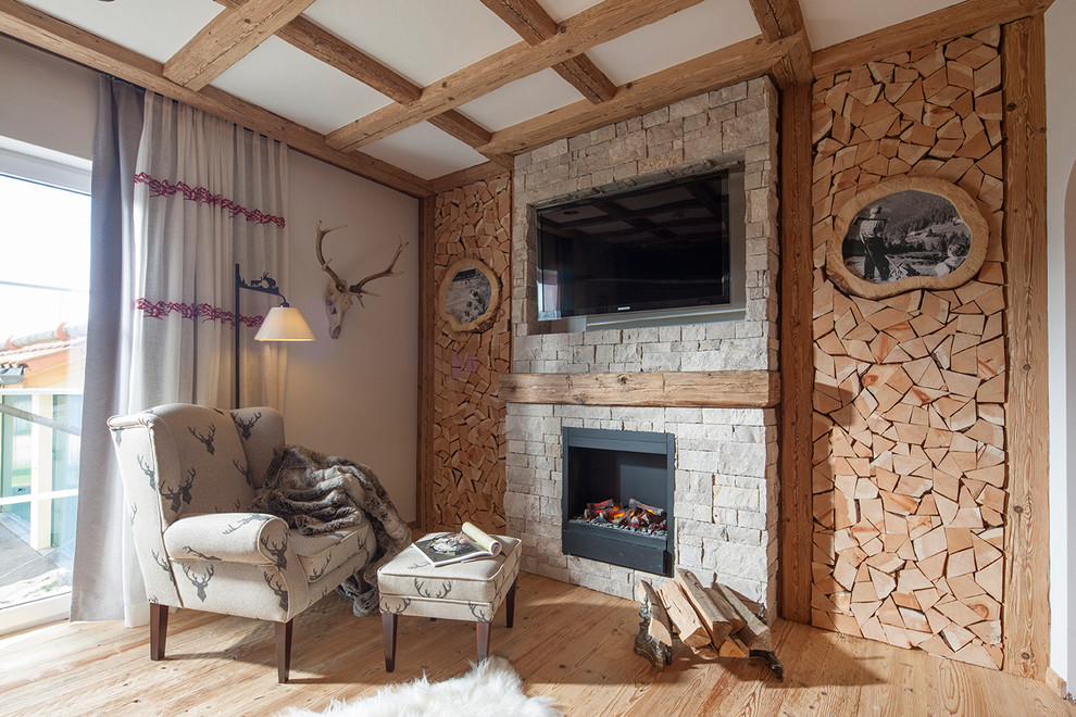 Ejemplo de salón abierto rural con suelo de madera clara, todas las chimeneas, marco de chimenea de piedra, televisor colgado en la pared y piedra