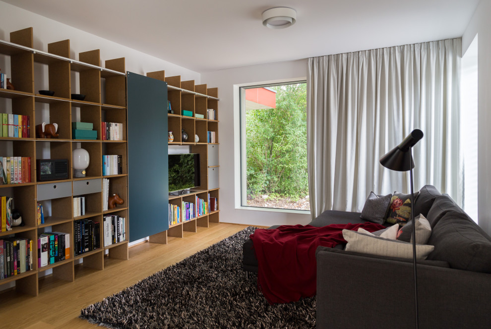 Offenes Modernes Wohnzimmer ohne Kamin mit weißer Wandfarbe, braunem Holzboden und braunem Boden in München
