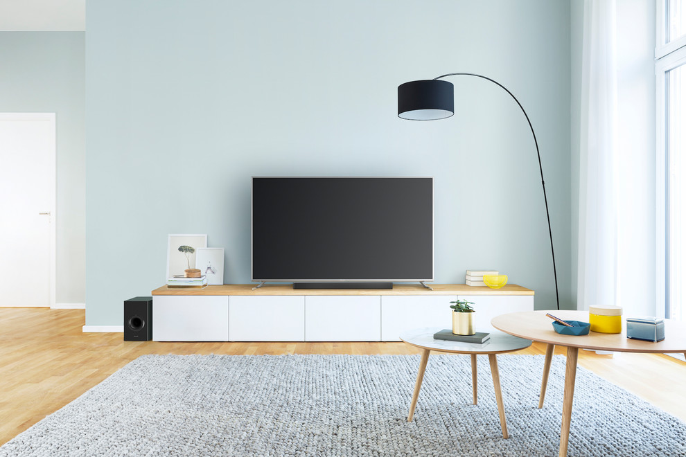 Foto di un soggiorno scandinavo di medie dimensioni e aperto con pareti blu, pavimento in legno massello medio, TV autoportante e pavimento marrone